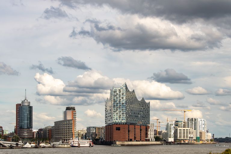 Scenic view of the Elbphilharmonie and Hamburg skyline along the waterfront with cloudy sky.