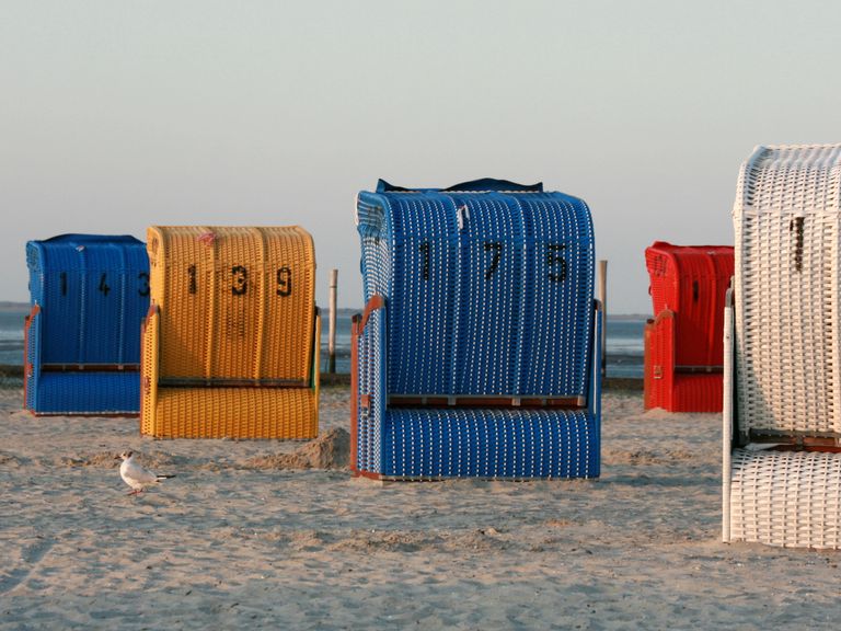 Vibrant wicker beach chairs on a sandy coastal setting, perfect for summer recreation.